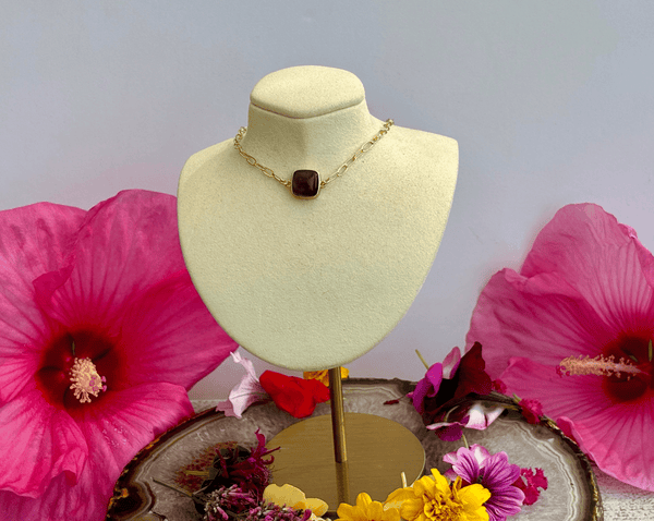 The Amethyst Square on 16 in 14KGF Vintage Paper Clip Chain by Amazing Earth is displayed on a cream bust, surrounded by colorful flowers. This elegant necklace adds charm to any crystal jewelry collection.