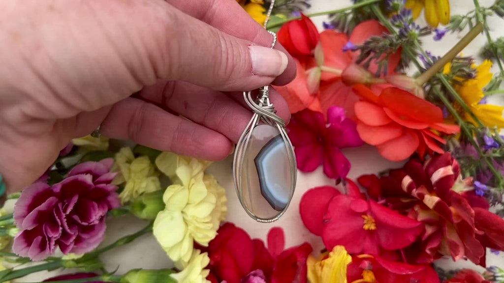 Montana Agate pendant on table with flowers. 